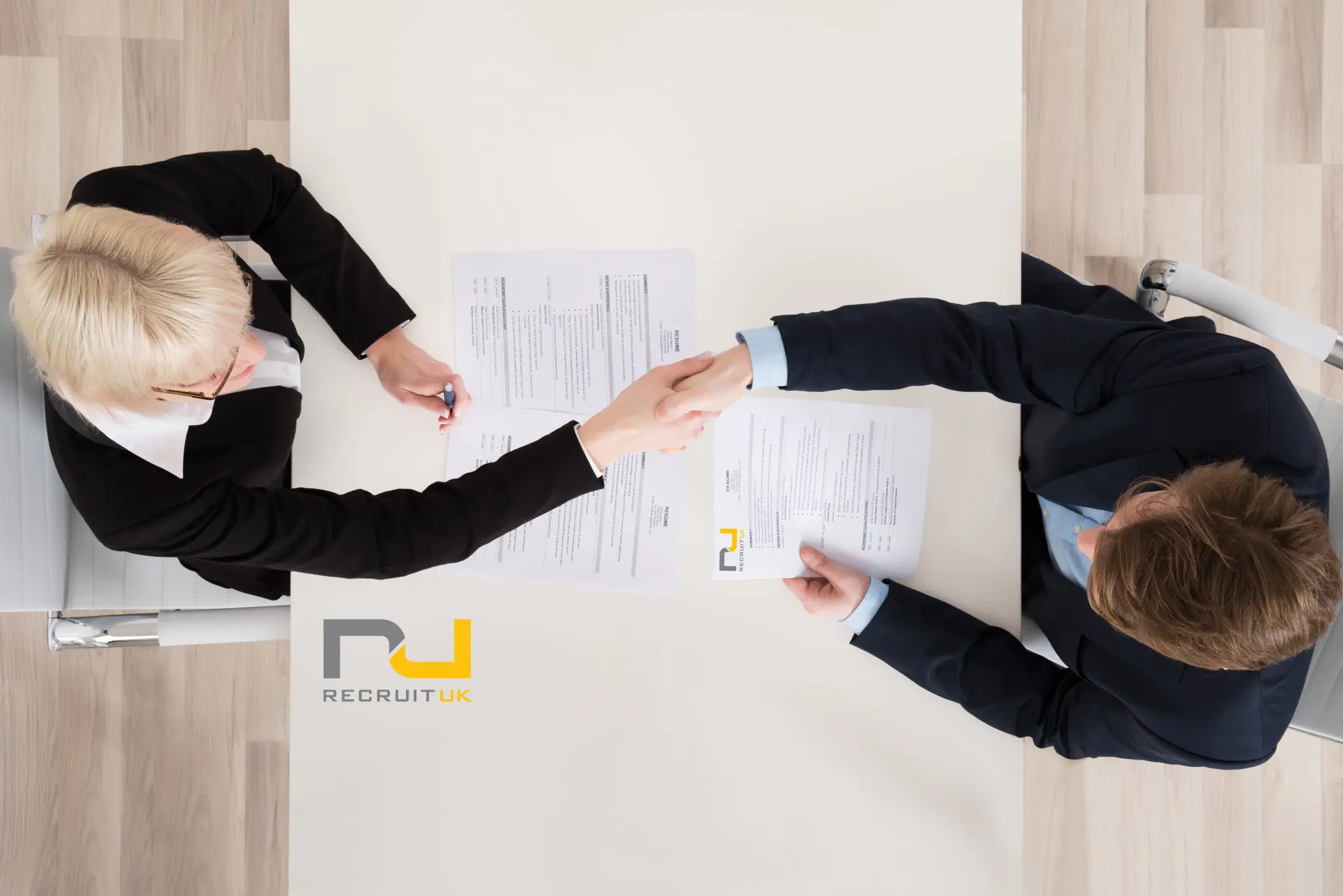 Birdseye view of people shaking hands with signed forms on the desk