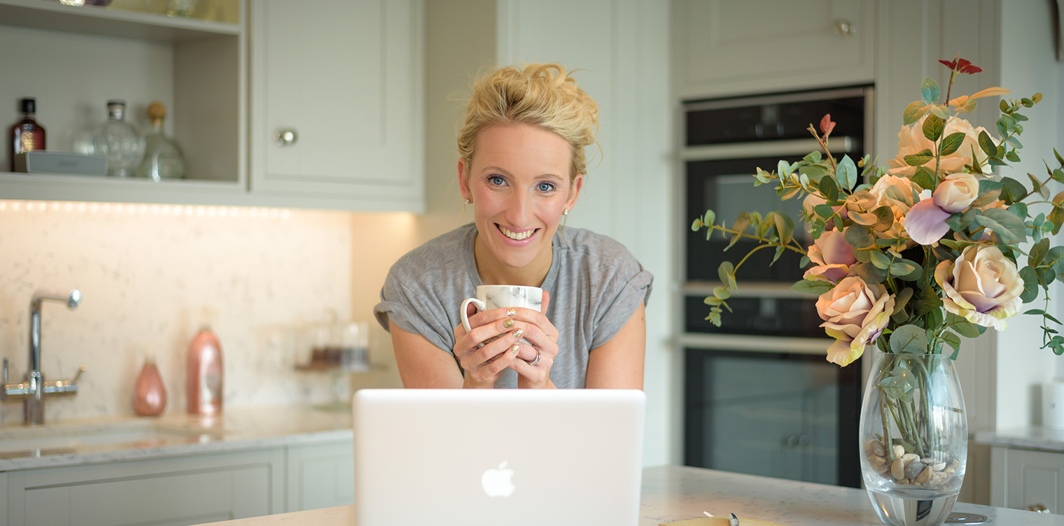 Photo of a lady in front of her laptop in her kitchen